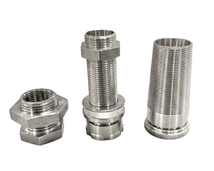 Trois raccords filetés en acier inoxydable : un écrou double, un passe-paroi avec écrou et rondelle, et un manchon fileté.